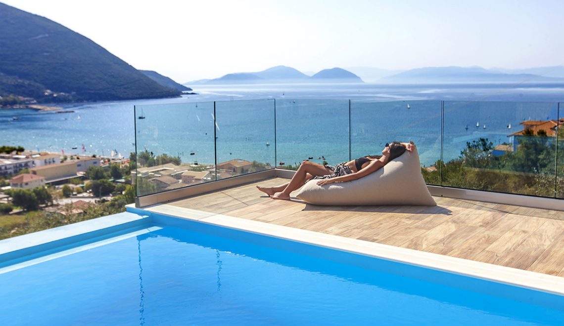 Villa Irene in vasiliki lefkada, girl on cushion of the private swimming pool admiring the sun and the panoramic sea-mountain view