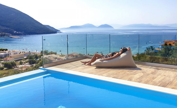 Villa Irene in vasiliki lefkada, girl on cushion of the private swimming pool admiring the sun and the panoramic sea-mountain view